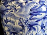 a blue and white vase with a bird and flowers on it