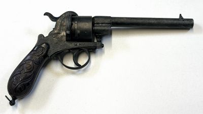 un vieux pistolet avec une poignée en bois sur une surface blanche