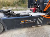 a black semi truck with orange stripes parked on the side of the road