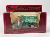 un petit camion vert dans une boîte rouge posée sur une surface blanche