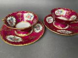 two cups and saucers with floral designs on them on a table