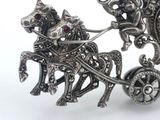 a silver brooch with a horse and carriage on it