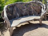 a bench made out of drift wood in the middle of a garden