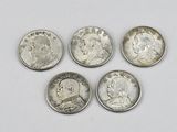 four different types of silver coins on a white surface
