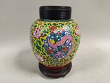 a colorful vase with a black lid sitting on a table