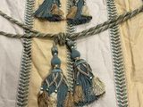 three tassels on a bed with a white and blue blanket