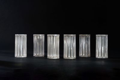 six clear glass vases are lined up on a black surface