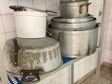 Plusieurs casseroles et poêles sont empilées sur une étagère dans une cuisine
