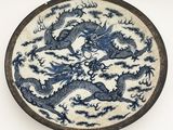 assiette bleue et blanche ornée d'un motif de dragon sur fond blanc