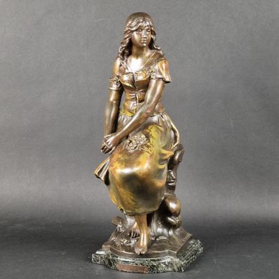 une statue en bronze représentant une femme assise sur un globe terrestre