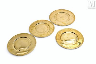 quatre assiettes plaquées or sur un fond blanc