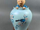 une figurine représentant un homme assis dans un vase bleu