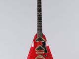 a red guitar hanging from a string on a white wall