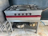 a silver stove with a red burner and two pots on it