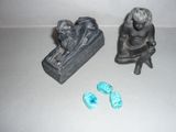 une petite statue représentant un homme assis sur un banc à côté d'une paire de chaussures