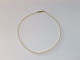 un collier de perles blanches avec une chaîne en or posé sur une surface blanche