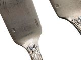 two forks that are sitting side by side on a white surface
