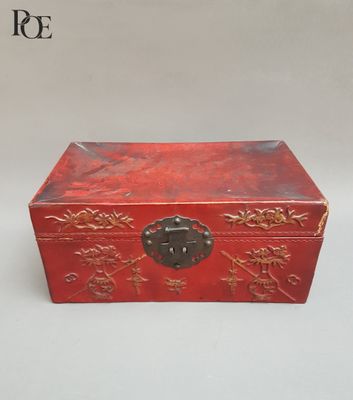 une petite boîte rouge ornée de motifs dorés