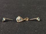 a pair of gold earrings with oplites on a black surface