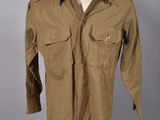 une chemise marron posée sur un présentoir à mannequin, sur fond gris