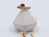 a close up of a gold ring with green stones on it