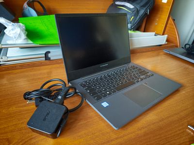 un ordinateur portable posé sur un bureau, avec un chargeur dessus