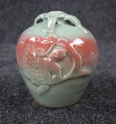 un vase vert orné d'un motif rouge et blanc