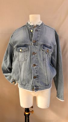 une veste en jean posée sur un support de mannequin dans une vitrine de mannequins