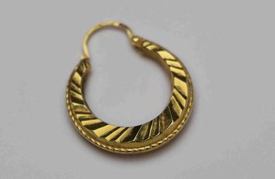 gros plan d'une paire de boucles d'oreilles en or sur une surface blanche