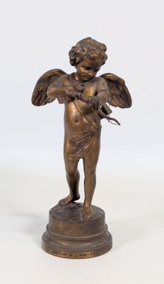 figurine en bronze représentant un ange tenant un oiseau, posée sur un socle
