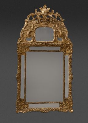 un miroir richement sculpté, avec un cadre doré sur fond gris
