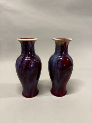 une paire de vases violets posés sur une surface blanche, sur fond blanc