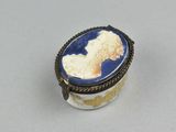 an oval blue and white broochee with a woman ' s profile on it