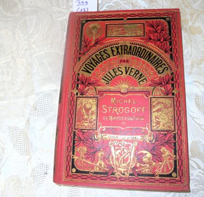 an old red book sitting on top of a table next to a ruler