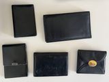 four black leather wallets and a cell phone sitting on a table