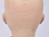 a clay head of a doll with a red and white dress