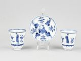 three blue and white porcelain cups and a saucer on a stand