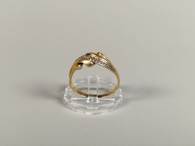 un gros plan d'une bague en or sertie de diamants posée sur une surface transparente