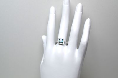 une bague sur la main d'un mannequin, sertie d'une pierre verte