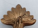 a gold plate with a leaf on it on a table