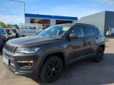 une Jeep Compass grise garée devant un immeuble