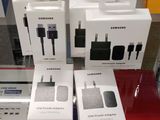 Trois boîtes d'adaptateurs secteur Samsung sont posées sur une table