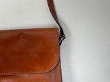a brown purse with a brown strap hanging from it