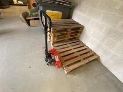 a small hand truck with pallets on it in a garage