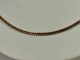 a close up of a gold necklace on a white surface