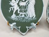 two decorative plates with angels on them sitting on a table