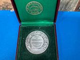 a silver medal in a green box on a blue table