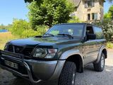 une photo d'un SUV vert garé devant une maison