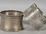pair of antique silver napkins with designs on them on a table