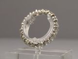 a silver ring on a clear stand on a white surface